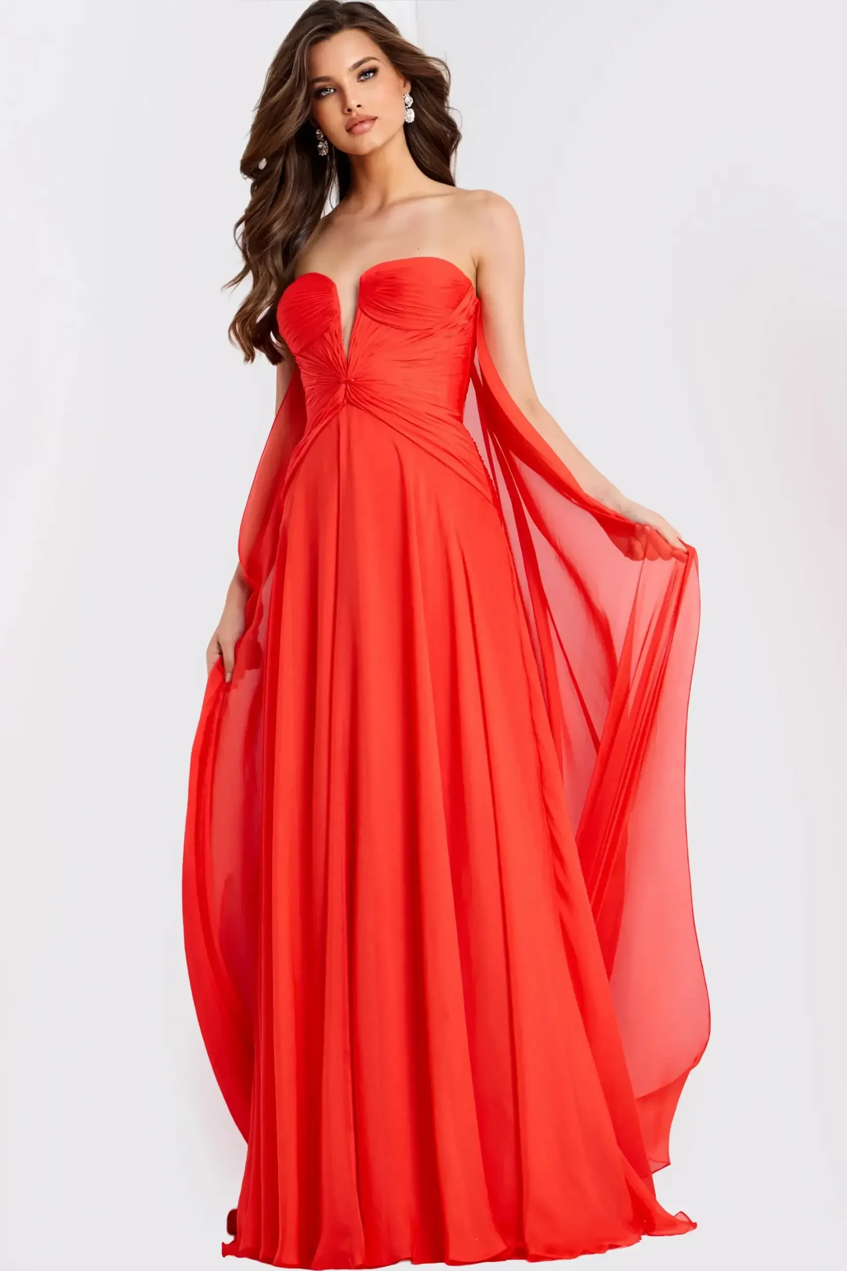 A woman in a strapless red evening gown with a flowing cape.
